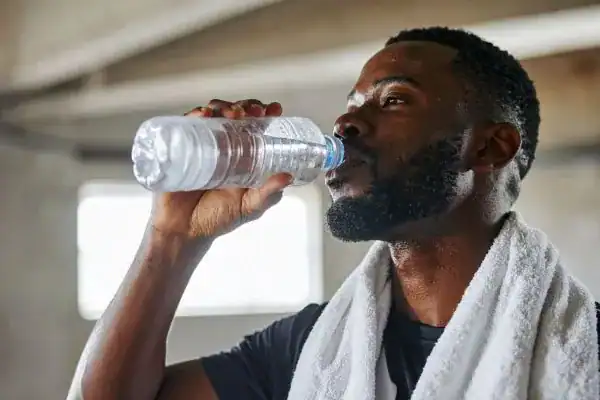 Image of man drinking water to improve hydration Berkshire after work out.